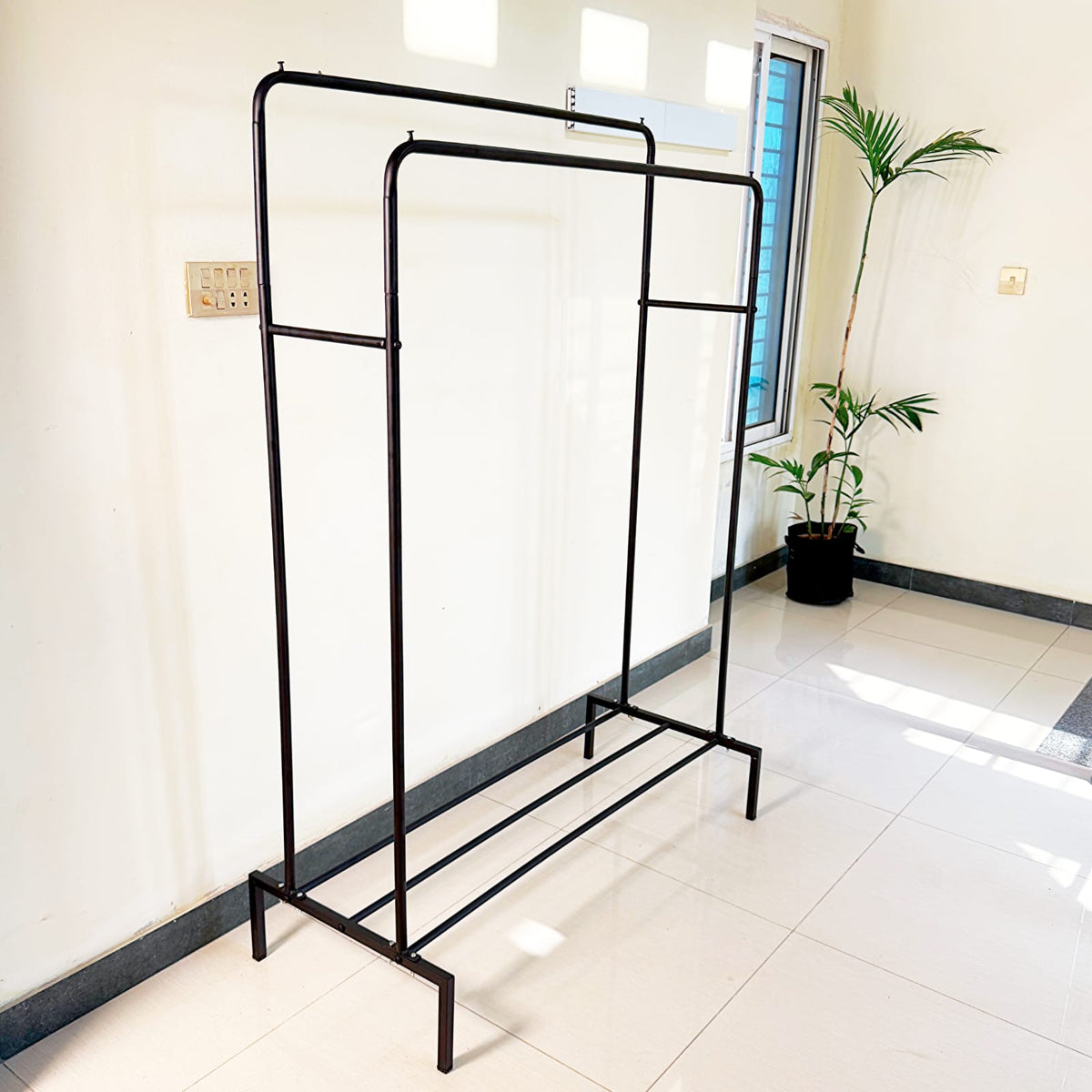 Metal Clothes Stand by Metallics Home featuring a sturdy frame with side storage shelves and hooks, set against a bright inte