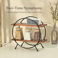 Orbit Duo Shelf by Metallics Home features two wooden shelves supported by a circular black metal frame, displaying decorativ