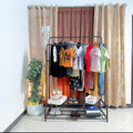 Dual Pole Metal Clothes Stand by Metallics Home featuring clothes on hangers, dual shoe tiers, and a decorative plant.