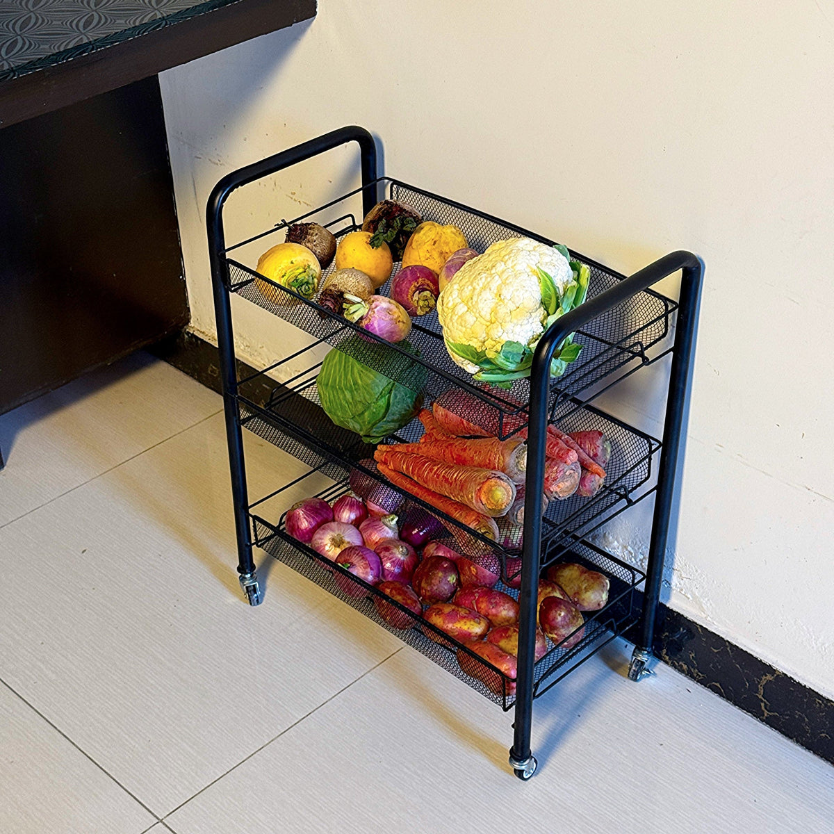 Multipurpose Foldable Kitchen Trolley by Metallics Home with three mesh shelves, holding various fresh vegetables and fruits.