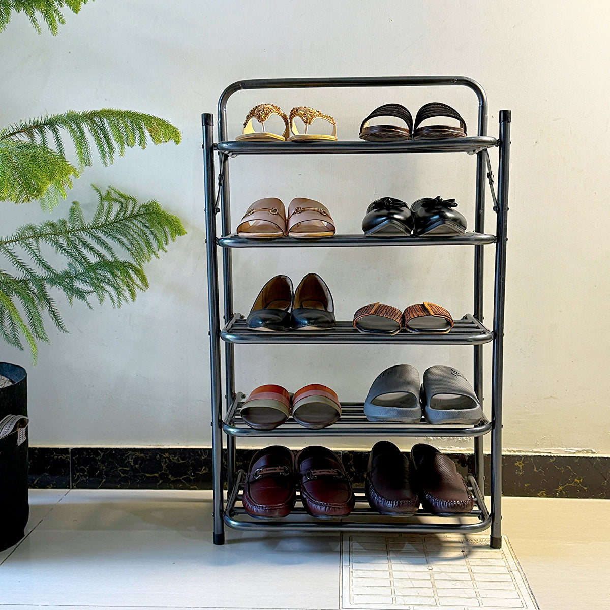 Foldable Metal Shoes Rack by Metallics Home with four shelves displaying various pairs of shoes, set against a neutral wall.