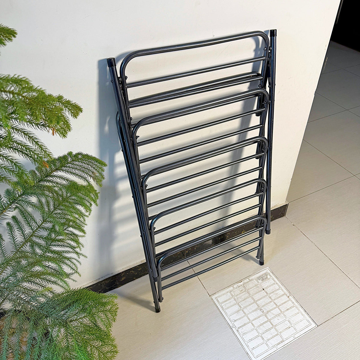 Foldable Metal Shoes Rack by Metallics Home, featuring a sleek black design, stacked against a wall for space-saving storage.