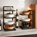 Floor Standing Kitchen Shelf by Metallics Home featuring black metal frame, wooden bowls, cookware, and wine bottles.