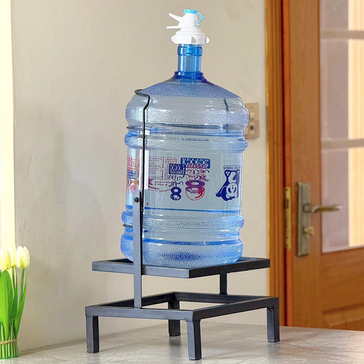 Swinging Bottle Rack by Metallics Home holds a large blue water bottle on a sleek black metal stand, ideal for kitchens.