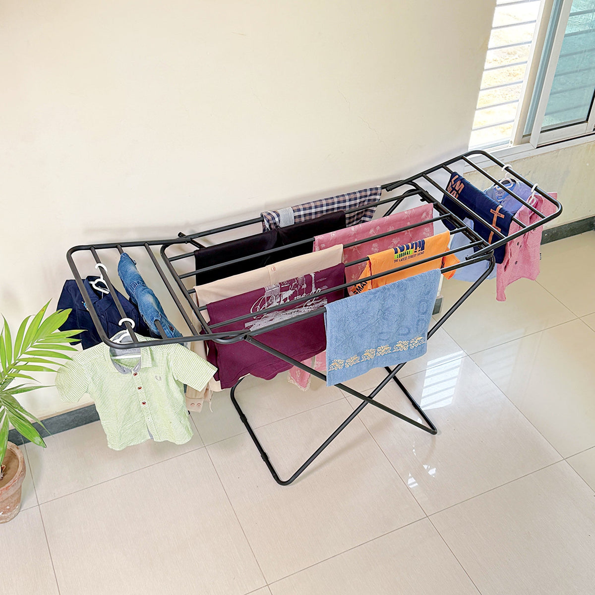 Premium Metal Folding Cloth Dryer Stand by Metallics Home with clothes hanging on it, set against a light-colored wall.